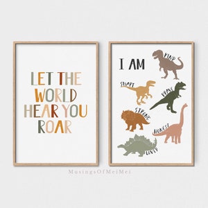Pode incluir: Duas impressões artísticas emolduradas com tema de dinossauros. Uma impressão diz "LET THE WORLD HEAR YOU ROAR" em várias cores. A outra impressão diz "I AM" com ilustrações de dinossauros e palavras como "KIND" e "BRAVE".