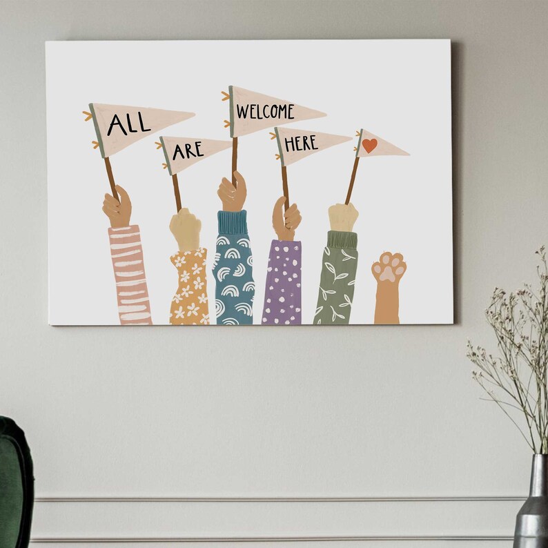 May include: A canvas print featuring illustrations of hands holding pennant flags. The flags read "ALL ARE WELCOME HERE" with a heart symbol. The hands have various sleeve designs, including stripes, flowers, and leaves. A cat paw is also included.