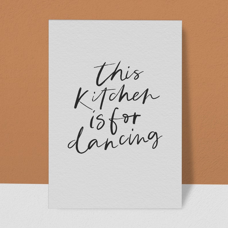 May include: A white card with black handwritten text that reads "This kitchen is for dancing".