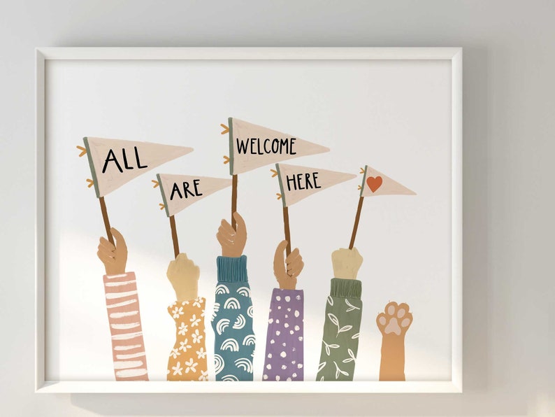 May include: A framed art print featuring hands holding pennant flags that read "ALL ARE WELCOME HERE." The hands have diverse skin tones and wear patterned sleeves. One paw print is also visible. The flags are beige with brown poles.