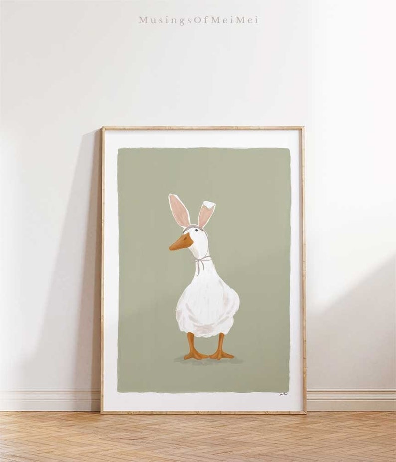 May include: A white duck wearing pink bunny ears stands on a sage green background. The duck is looking to the left of the image.