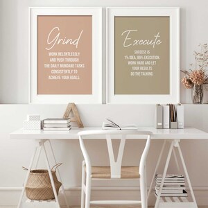 May include: Two framed motivational posters with beige and brown backgrounds. The left poster has the word "Grind" in white script and the text "Work relentlessly and push through the daily mundane tasks consistently to achieve your goals." The right poster has the word "Execute" in white script and the text "Success is 1% idea, 99% execution. Work hard and let your results do the talking."