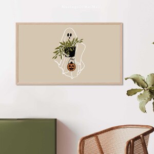 May include: A white outline of a ghost holding a potted plant and a small orange jack-o'-lantern. The ghost is on a beige background.