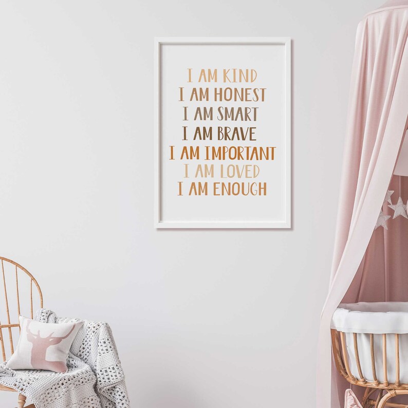 May include: A framed print with the words "I AM KIND, I AM HONEST, I AM SMART, I AM BRAVE, I AM IMPORTANT, I AM LOVED, I AM ENOUGH" in a copper color. The print is in a white frame, hanging on a white wall.