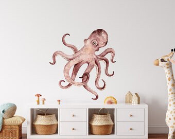 May include: A watercolor illustration of a pink octopus with eight tentacles, on a white wall above a white dresser with two drawers. The dresser has three baskets on top, and a stuffed giraffe is on the right side of the image.