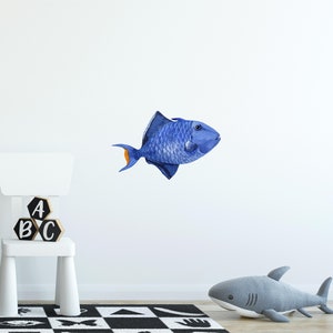 May include: A blue and orange fish wall decal with a white background. The fish is swimming to the right. The decal is perfect for a child's room or nursery.