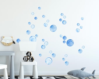 Op de afbeelding: Blauwe waterverf bubbel wanddecoratie voor een kinderkamer of babykamer. De stickers zijn willekeurig op een witte muur geplaatst.