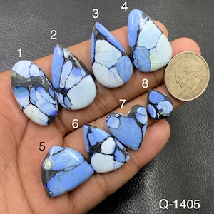 Puede incluir: Ocho cabujones pulidos de color azul y blanco con vetas oscuras, numerados del uno al ocho, mostrados junto a una moneda de veinticinco centavos de EE. UU. para escala. Las piedras presentan formas variadas como gota, óvalo y corazón.
