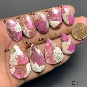 May include: A collection of nine polished pink and white cabochon gemstones labeled with numbers 9 through 17, displayed alongside a copper penny for scale. Each stone features unique mottled patterns of vibrant pink and creamy white mineral inclusions.