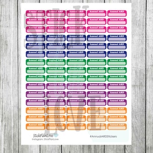Op de afbeelding: Een vel met kleurrijke stickers met de tekst "Annual ARD" en een lege ruimte om te schrijven. De stickers zijn in verschillende kleuren, waaronder roze, blauw, groen, paars en oranje.