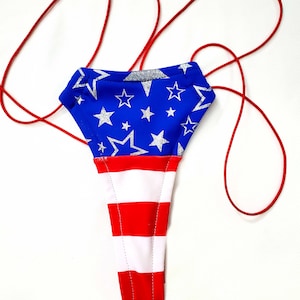 May include: A red, white, and blue swimsuit with a star pattern on the top and stripes on the bottom. The swimsuit is tied with red strings.