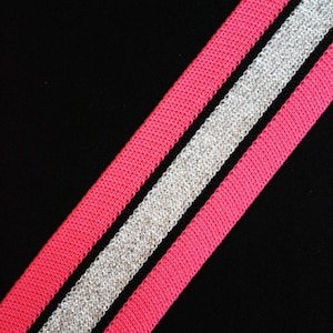 May include: A pink and silver striped fabric with a diagonal pattern. The fabric is woven with a textured, sparkly silver thread.