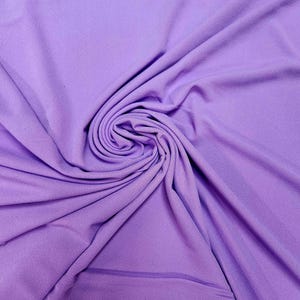 May include: A close-up of a soft, smooth, purple fabric. The fabric is draped and folded, creating a swirling pattern.