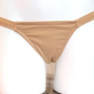 May include: A nude-colored bikini bottom with a simple design. The bottom has a wide waistband and a low-cut leg opening.