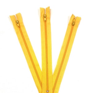 May include: Three yellow zippers with gold pulls. The zippers are labeled "Athletic/Light Gold".