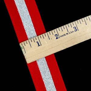 May include: Red and silver striped ribbon with a ruler measuring 1 inch.