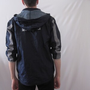 May include: A navy blue hooded jacket with gray accents and a white logo that says "Lee Cooper".