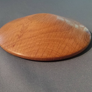 May include: A round, light brown wooden lid with a slightly domed top.