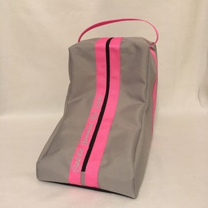 May include: Gray boot bag with a pink and black zipper and a pink strap. The bag has the text "Saddle Jockeys By Susie" embroidered on the side.