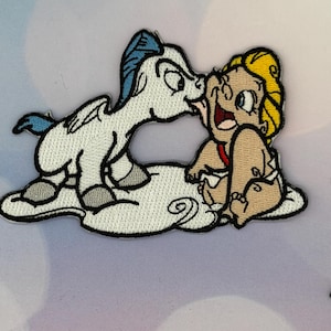 Könnte beinhalten: Gestickter Aufnäher mit einem Cartoon-Pegasus, der ein Baby küsst. Der Pegasus ist weiß mit blauen Akzenten, und das Baby hat blondes Haar und einen roten Träger. Beide befinden sich auf einer weißen Wolke mit schwarzen Umrissen.