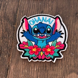 May include: Embroidered patch featuring Stitch from Lilo & Stitch, with the word "Ohana" above him. Stitch is blue with big eyes and a toothy grin. He is surrounded by pink and red flowers.