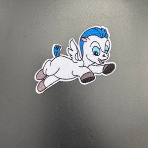 Könnte beinhalten: Weißer gestickter Aufnäher mit einem Cartoon-Pegasus mit blauen Flügeln und einer blauen Mähne, der mit einem glücklichen Ausdruck fliegt.