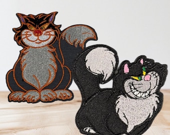 May include: Two embroidered patches of black cats with white fur. The cat on the left is sitting with its tail curled around its body. The cat on the right is lying down with its tail curled behind it. Both cats have green eyes and a mischievous grin.