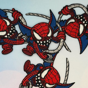 Könnte beinhalten: Gestickte Aufnäher mit einer Comicfigur in einem rot-blauen Kostüm mit Spinnennetz-Design. Die Figur hat ein bedrohliches Grinsen und hält ein silbernes, netzartiges Accessoire. Die Aufnäher sind mit weißen, schwarzen und roten Nähten detailliert.