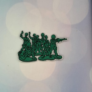 May include: An embroidered patch featuring a group of six green toy soldiers in various poses, including standing, kneeling, and aiming rifles. The figures are rendered in a dark green thread with a white border, depicting a classic military squad.