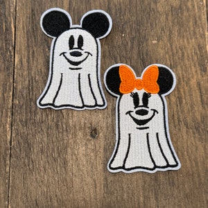 Può includere: Due toppe ricamate a forma di fantasma bianche con volti neri di Topolino e Topolina. Topolino ha orecchie nere e Topolina ha orecchie nere con un grande fiocco arancione.