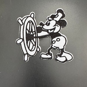 May include: Black and white embroidered iron-on patch of Mickey Mouse dressed as a sailor, holding a ship's wheel.