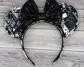 May include: Black and white mouse ears headband with a black sequined bow. The ears feature a black and white print with a graphic design.
