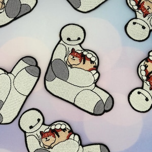 May include: Embroidered patches featuring a white robot character holding a small, orange and brown Shiba Inu dog. The robot has a simple design with a black curved mouth and gray accents. The dog is curled up in the robot's arms.