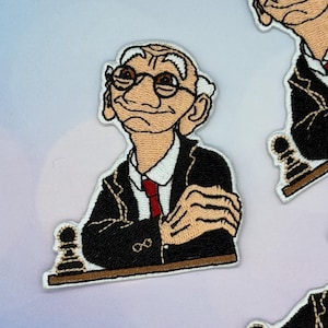 May include: Embroidered patch featuring a cartoon of an elderly man wearing glasses, a red tie, and a black suit. The man is positioned above a chess piece. The patch has a white border and is likely for clothing or accessories.