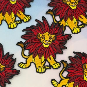 Puede incluir: Parches bordados con un león de dibujos animados con melena roja y cuerpo amarillo. Los parches están detallados con contornos negros y son adecuados para decorar ropa o accesorios.