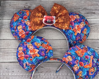 May include: A pair of blue and orange mouse ears with a bow. The ears feature a repeating pattern of characters from the movie Turning Red. The bow is made of orange sequins.