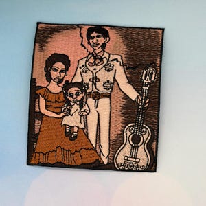 May include: Embroidered patch with a family portrait illustration. The patch shows a man in a white suit holding a guitar, a woman in a brown dress, and a young girl in a white dress. The background is a light pink colour.