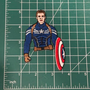 May include: Embroidered patch featuring Captain America in his iconic blue, white, and red costume, holding his shield. The patch is approximately 3 inches tall and 2 inches wide.