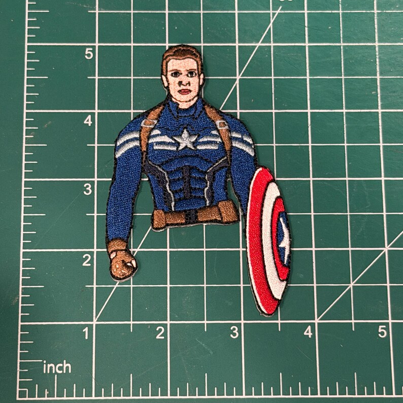 May include: Embroidered patch featuring Captain America in his iconic blue, white, and red costume, holding his shield. The patch is approximately 3 inches tall and 2 inches wide.