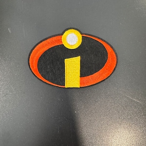 Può includere: Una toppa ricamata rossa e gialla con la lettera "I" all'interno di un cerchio. La lettera "I" è gialla e il cerchio è rosso con un contorno giallo.