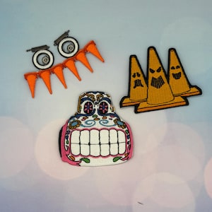 Puede incluir: Un conjunto de parches bordados. Uno es una calavera de azúcar con forma de coche con diseños florales y geométricos. Otros incluyen conos de tráfico naranjas y un juego de ruedas. Estos parches coloridos son ideales para decorar ropa o accesorios.