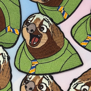 May include: Embroidered patches featuring a cartoon sloth with a surprised expression. The sloth has brown fur, a green sweater, and a blue and yellow tie. The patches are designed for clothing or accessories.
