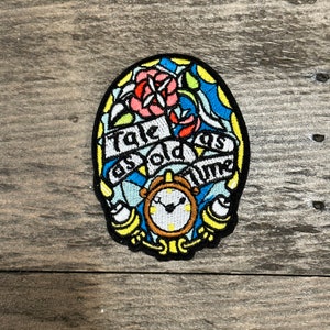 Può includere: Una toppa ricamata colorata con un orologio, una rosa e il testo "Tale as old as time".