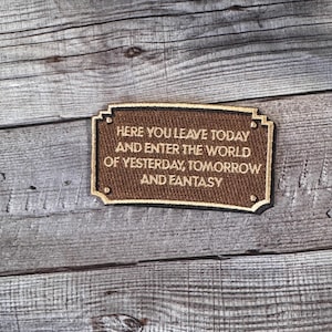 Puede incluir: Un letrero marrón con ribete dorado y el texto "Here you leave today and enter the world of yesterday, tomorrow and fantasy."