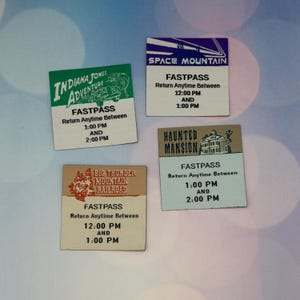 Può includere: Quattro biglietti Fastpass vintage da un parco a tema. I biglietti presentano i nomi "Indiana Jones Adventure", "Space Mountain", "Haunted Mansion" e "Big Thunder Mountain Railroad". Ogni biglietto mostra gli orari di ritorno tra le 12:00 e le 14:00.
