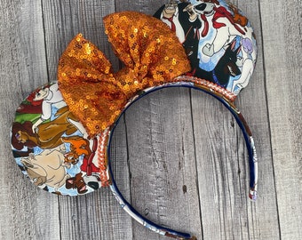 May include: Orange sequin bow headband with a cartoon dog print on the ears. The print features a group of dogs, including a Dalmatian, a bulldog, and a terrier.