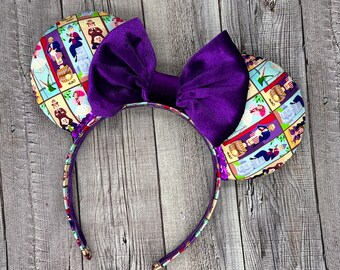 Puede incluir: Diadema de lazo de tela morada con un estampado colorido que presenta una variedad de personajes. El estampado incluye una variedad de colores, incluyendo morado, azul, amarillo y verde.