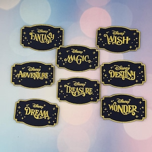 May include: A collection of navy blue embroidered patches with gold lettering and borders. Each patch features a Disney-themed word: Fantasy, Wish, Magic, Adventure, Destiny, Treasure, Dream, and Wonder. Stars and the Disney logo are also included.