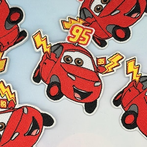 May include: Embroidered patches of a red cartoon car with the number '95' and lightning bolt details. The car has large eyes and a smiling face. The patches are set against a light blue backdrop.