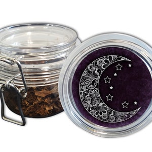 May include: A clear glass jar with a hinged metal clasp, partially filled with dried leaves. The lid features a crescent moon and star design in white against a dark purple background. The jar is designed for storage.